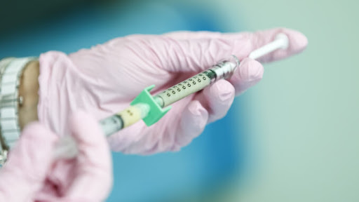 Vaccination being prepared for use on unknown patient. Administered by doctor.