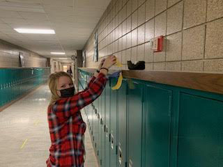FFA President Natalie Ott preparing for FFA week by hanging streamers in the hall outside the Ag room.