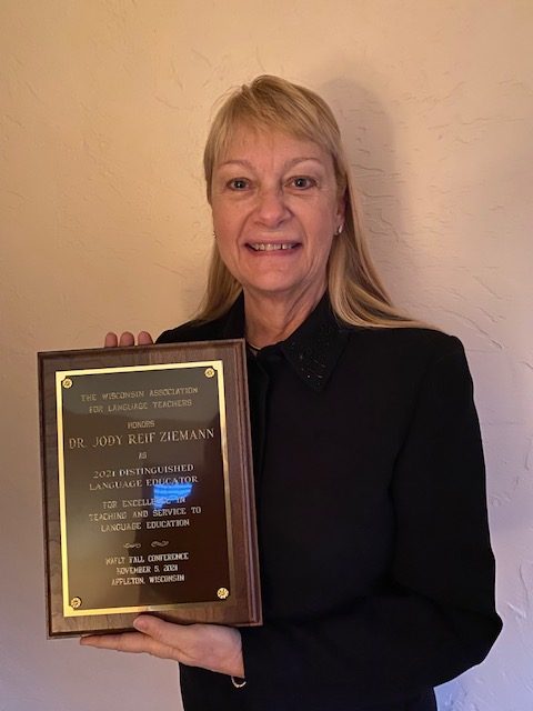 Spanish+teacher+Jody+Ziemann+holds+up+her+engraved+plaque+after+receiving+it+in+the+mail+the+night+of+the+virtual+conference.+Ziemann+has+officially+been+named+the+2021+Distinguished+Language+Educator.+%E2%80%9CI%E2%80%99m+also+going+to+get+a+%24500+honorarium%2C+but+I+haven%E2%80%99t+quite+figured+out+what+I%E2%80%99m+going+to+do+with+that%2C%E2%80%9D+Ziemann+said.+