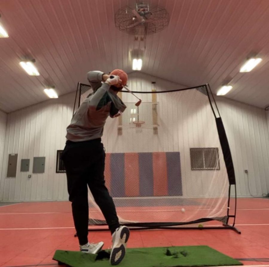 Junior Frank Kujawa practices his swing inside to prepare for the upcoming season. The team had to get creative to keep their swings in shape. “I have been practicing on a mat hitting into a net at home and we have been going to golf simulators,” Kujawa said.