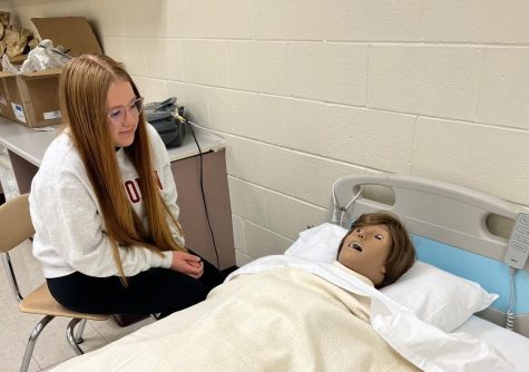 CNA student senior Madison Mertens examines mannequin for new CNA class.  