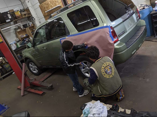 Sophomore Eliel Abreu (right) works on taping the rear fender of a 2008 Ford Escape. He has worked on many cars over the years.

