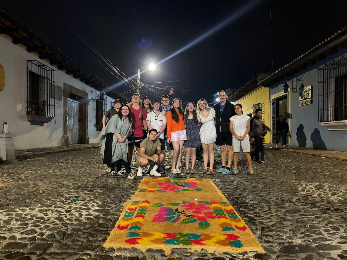 	Berlin students and students and staff from a nearby school in Antigua pose with the sawdust carpet for the procession. The group worked on the carpet for about two hours before the procession came and ran it over.