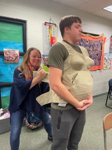 Senior Michael Sahotsky getting strapped into the empathy belly by family and consumer science teacher Missy Daubner. “At first I was like oh this is going to be easy just a couple extra pounds then she put the bag that passes on my bladder, and the lead balls to simulate elbows and knees and at that point I was like wow this is gonna be tougher than I thought,” Sahotsky said.
