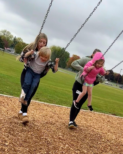 Junior Mia Ledesma enjoys recess at the Clay Lamberton playground with the kindergartners while pushing a young boy on the swingset.