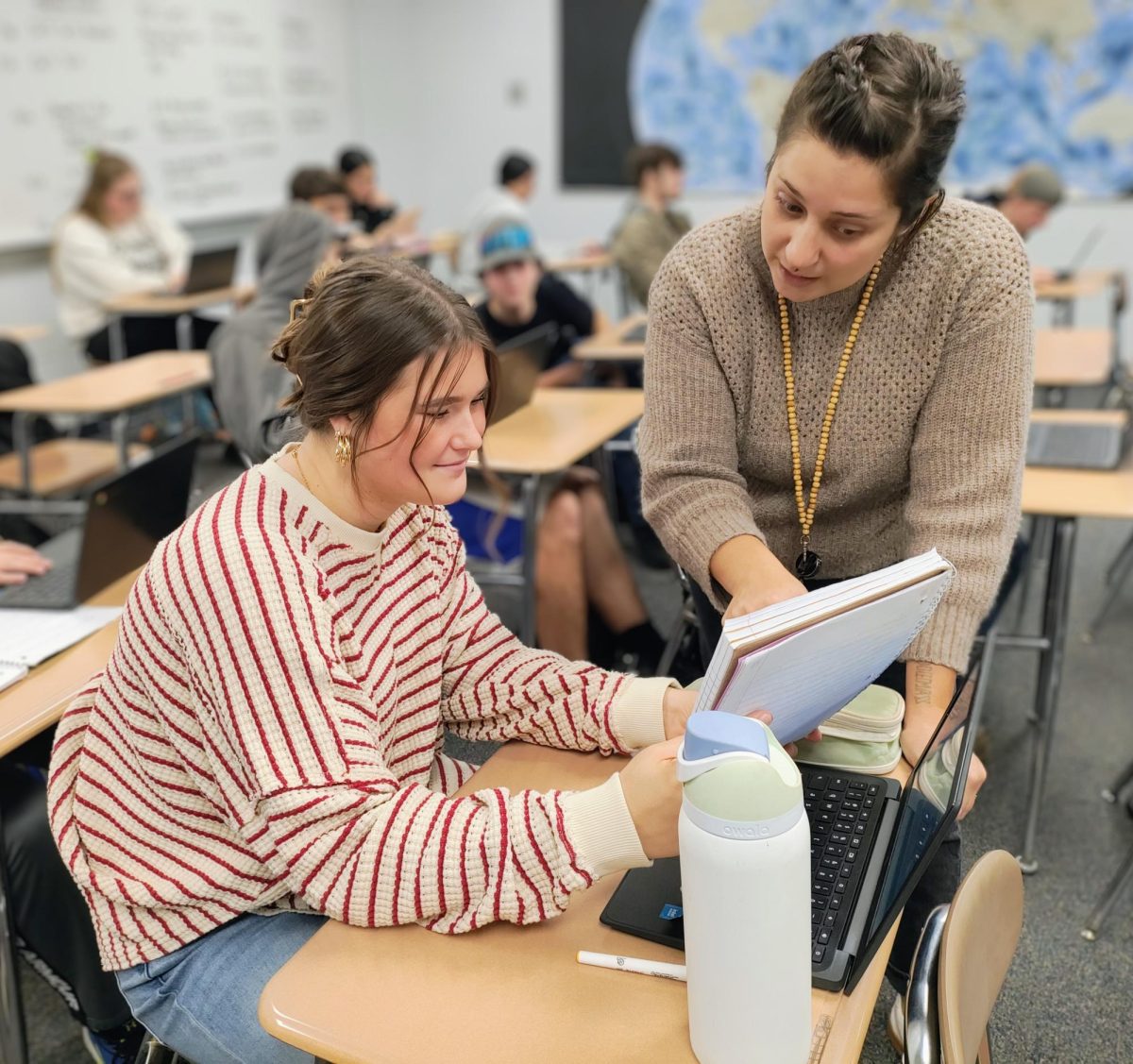The new social studies long-term substitute Christina Buehner helps a junior Kennady Bending with questions during worktime.