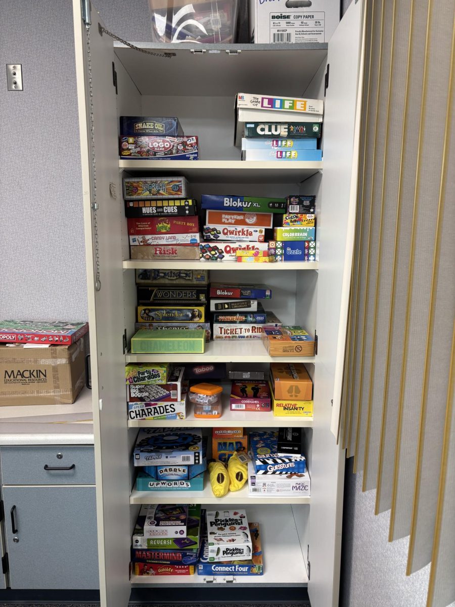A selection of board games sit in a cabinet. 