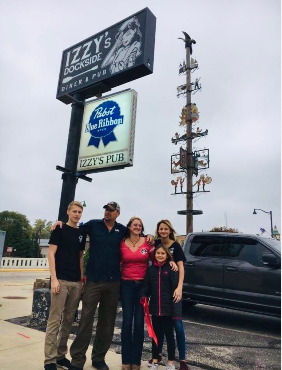 Left to right: Cole Jecevicus, Chris Jecevicus, Ajshe Jecevicus, Veda Jecevicus, Lola Jecevicus. The Jecevicus family stands in front of the sign after changing the restaurant's name from Berlin Family Dinner to Izzy’s. “Izzy’s and Berlin gave me so many opportunities and joy, but losing my dad was the final heartbreak, and I decided it was for the best to pass the torch of my beloved restaurant and pub,” Ajshe said. 
